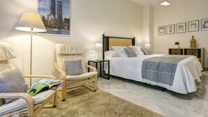 A hotel room with a bed, a chair, a bedside table, a lamp, a picture on the wall, and a floor lamp. - Spacious Bright With Excellent Location 1 Bd Aptm Tomas de Ibarra (Seville)
