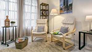 A room with two white armchairs, a floor lamp, a bookshelf, a potted plant, and a basket of magazines. - Spacious Bright With Excellent Location 1 Bd Aptm Tomas de Ibarra (Seville)