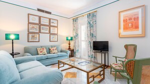 Un saló amb un sofà, una taula de centre, una televisió i quadres a la paret.