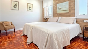 Een slaapkamer met een groot bed, houten lambrisering aan de muur en twee ingelijste foto's.