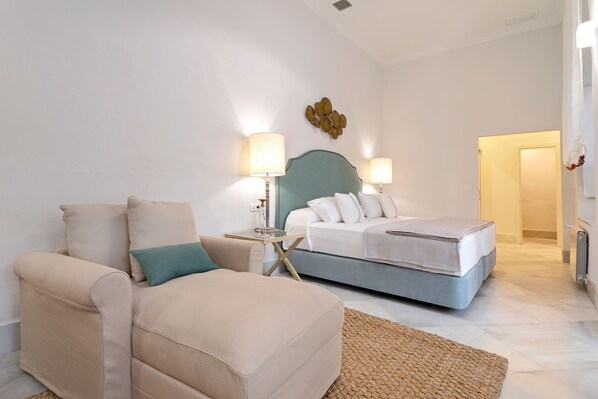 A bedroom with a bed, a sofa, and two bedside tables with lamps. - Unique Sevillian Palace-house in Santa Cruz Abades Terrace (Seville)