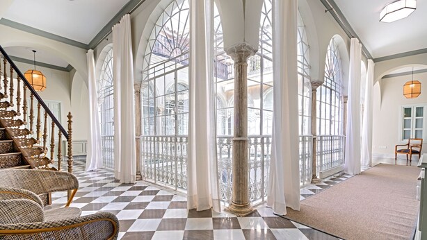 A grand interior with a checkered floor, large arched windows, and a staircase with ornate railings. - Unique Sevillian Palace-house in Santa Cruz Abades Terrace (Seville)