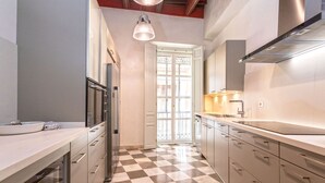 A modern kitchen with a checkered floor, stainless steel appliances, and a large window with a view. - Unique Sevillian Palace-house in Santa Cruz Abades Terrace (Seville)