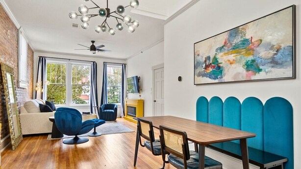 A modern living room with a wooden dining table, blue chairs, a sofa, and a fireplace.
