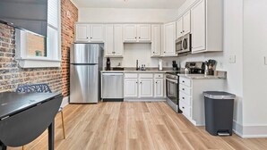 A modern kitchen with white cabinets, stainless steel appliances, and a brick wall. - Stylish Loft Retreat in Downtown Hot Springs (Hot Springs)