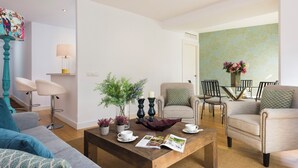 Un salon moderne comprenant un canapé, une table basse, un coin repas avec des chaises et un vase décoratif avec des fleurs.