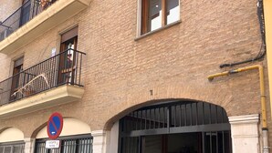 Un bâtiment dont l’entrée est protégée par des barreaux, sur lequel on peut lire un panneau indiquant qu’il est interdit de se garer, et devant lequel est stationnée une moto.