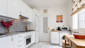 A modern kitchen with white cabinets, granite countertops, a microwave, a washing machine, and a wooden dining table. - Wonderful Large 4 BD Duplex With a Private Terrace Salvador Terrace (Seville)