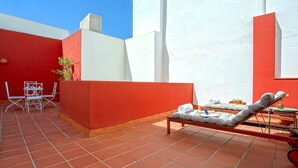 A red and white tiled patio with a lounge chair, a small table, and a metal chair. - Wonderful Large 4 BD Duplex With a Private Terrace Salvador Terrace (Seville)