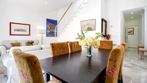 A dining area with a dark wooden table, floral upholstered chairs, and a vase of flowers. - Wonderful Large 4 BD Duplex With a Private Terrace Salvador Terrace (Seville)
