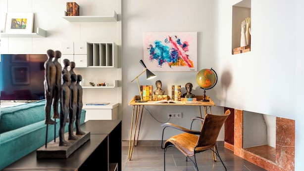 A modern living room with a sofa, a desk with a globe and busts, and a colorful abstract painting. - Wonderful Apartment 200m2 - 4 Bedrooms - 3 Bathrooms in the Best Location Albareda (Seville)