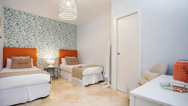 Ein Hotelzimmer mit zwei Betten, einem weißen Schreibtisch und einer Wand mit Muster.