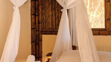 Een bed met witte lakens en een hemelbed.