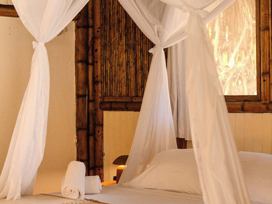 Een bed met witte lakens en een hemelbed.