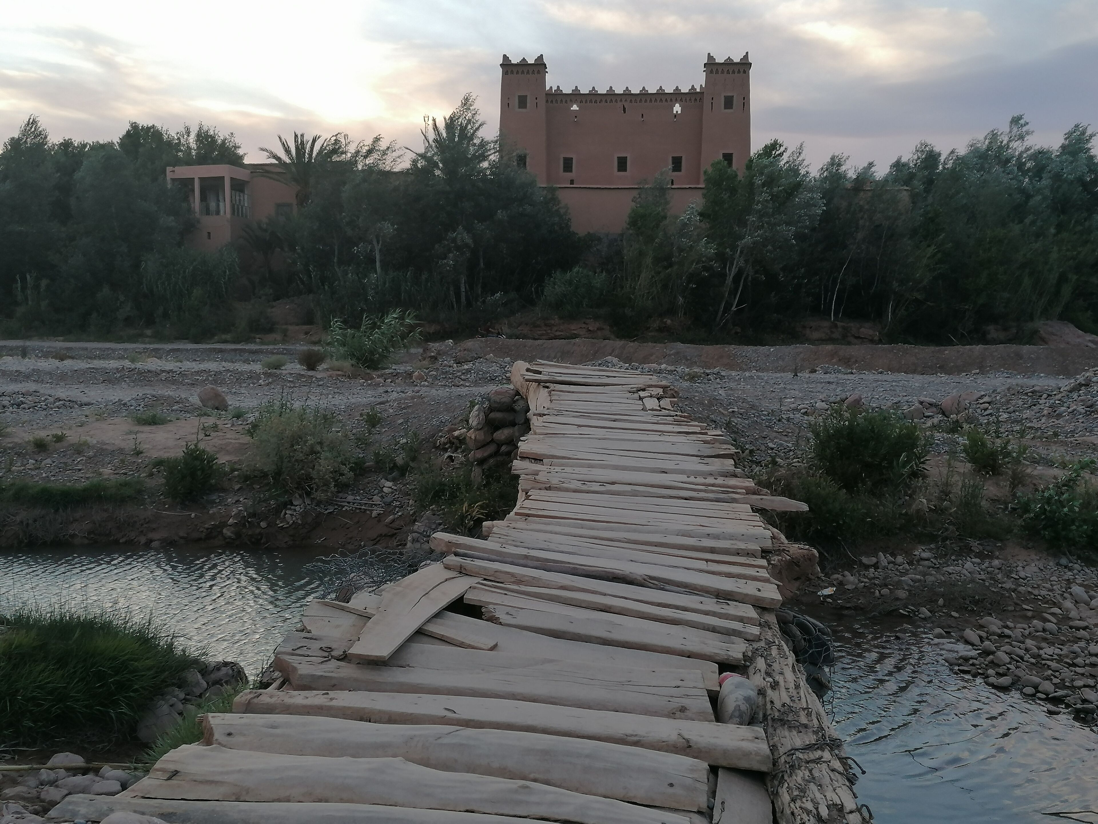 Un puente de piedra que conduce a un castillo con una torre.