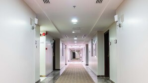 A long, narrow hotel corridor with a patterned carpet, white walls, and doors on both sides. - Dufla Hotel  (Makkah)