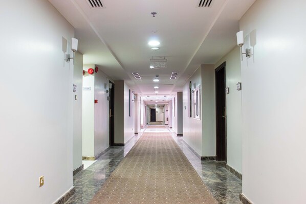 A long, narrow hotel corridor with a patterned carpet, white walls, and doors on both sides. - Dufla Hotel  (Makkah)