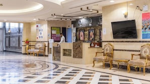 A hotel reception area with a marble floor, a reception desk, and a television mounted on the wall. - Dufla Hotel  (Makkah)