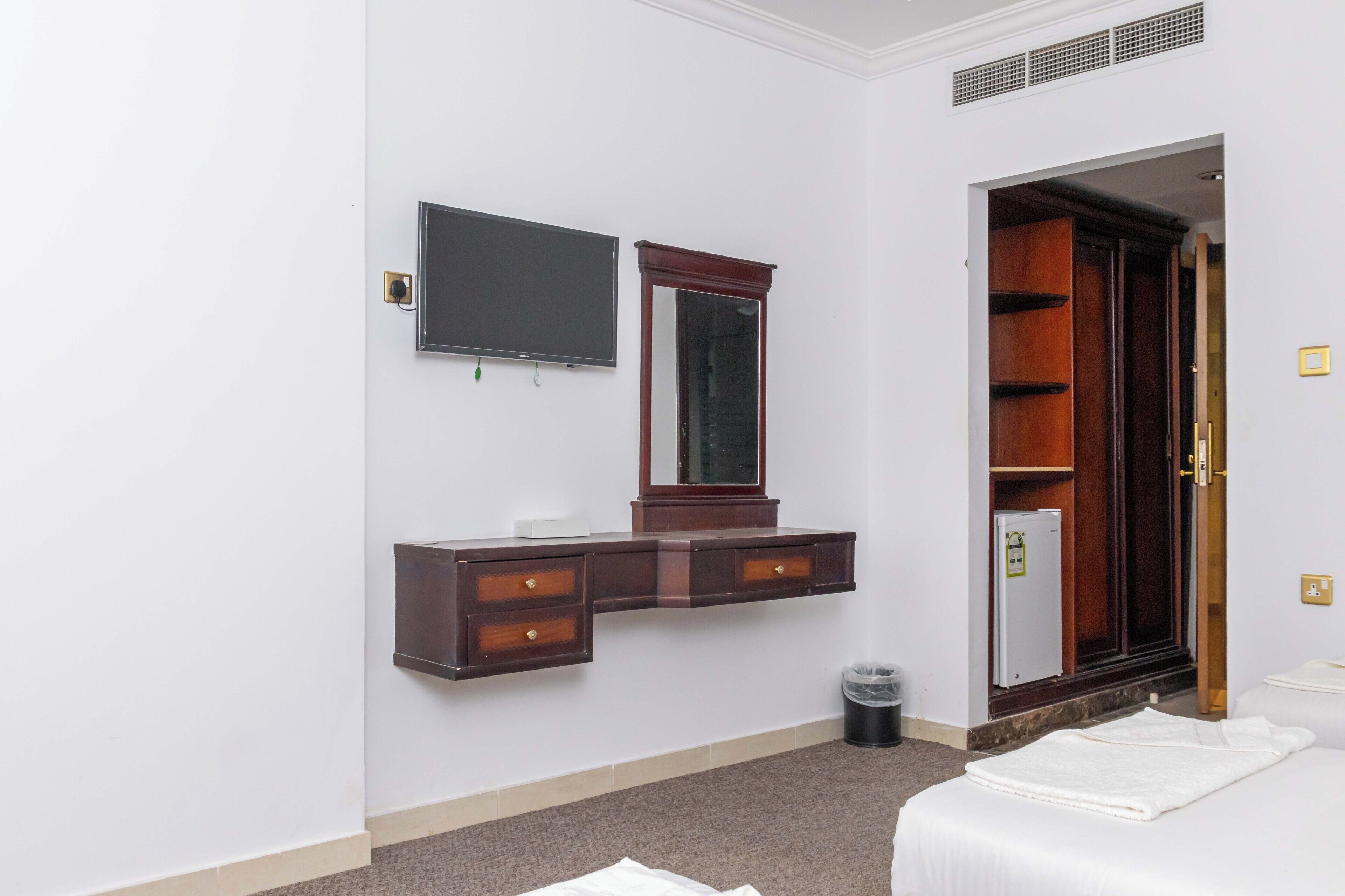 Une chambre d’hôtel comprenant un lit, une commode avec un miroir, une télévision et une armoire.