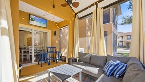 A sunlit room with a sofa, a coffee table, and a dining area with chairs and a table. - Regal Palms 4BR Home: Water Park Fun! (Davenport)