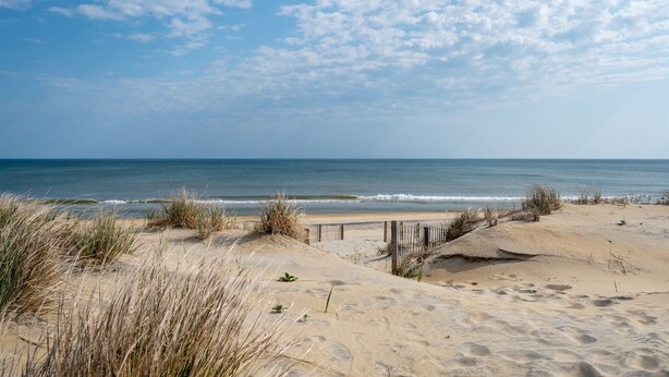 A sandy beach with dunes and a wooden fence leading to the ocean. - Semi-Oceanfront, Ocean Views! 225ft to Beach! -Pool, Hot Tub,Pool Table,Dogs OK! (Kitty Hawk)