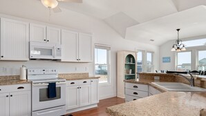 A modern kitchen with white cabinetry, a built-in oven, a microwave, and a granite countertop. - Semi-Oceanfront, Ocean Views! 225ft to Beach! -Pool, Hot Tub,Pool Table,Dogs OK! (Kitty Hawk)