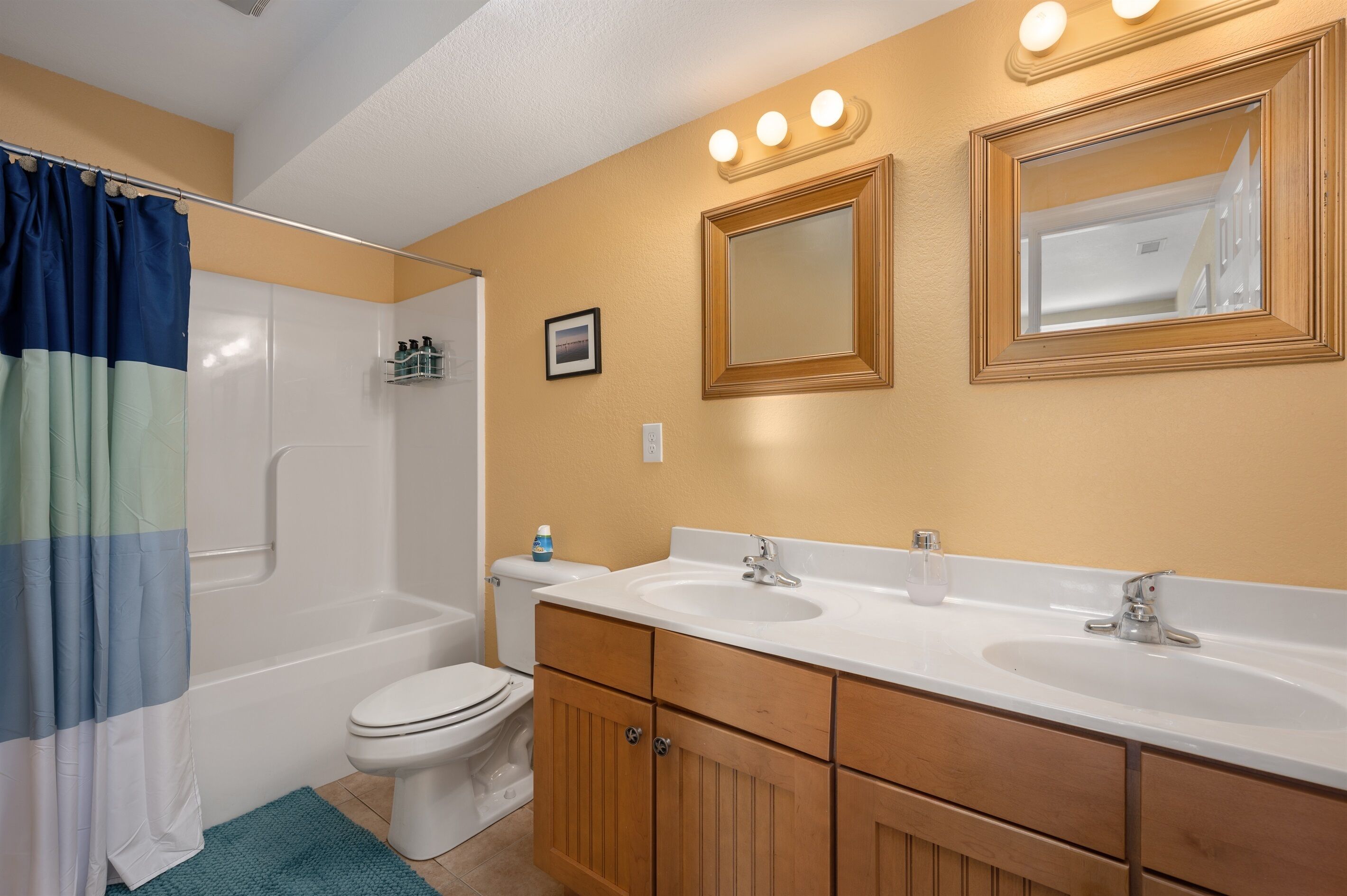 A bathroom with a shower, toilet, and double sink vanity.