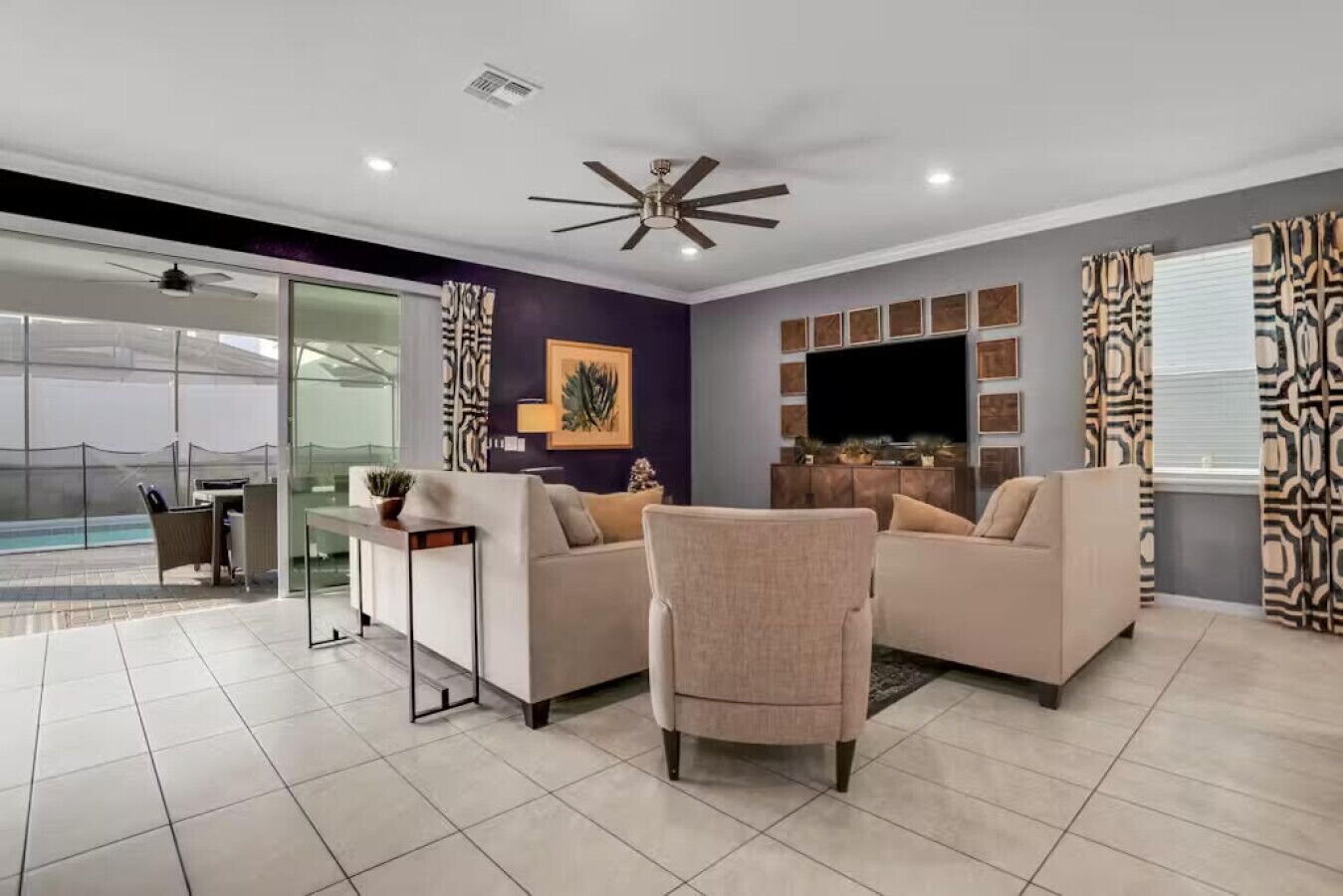 A modern living room with two sofas, a coffee table, a TV, and a ceiling fan.