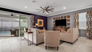 A modern living room with two sofas, a coffee table, a TV, and a ceiling fan.