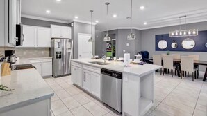 A modern kitchen with white cabinetry, a central island, and pendant lighting.