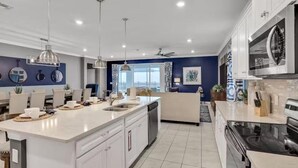 A modern kitchen with a large island, white cabinetry, and a blue accent wall.