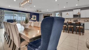 A modern dining area with a wooden table, blue upholstered chairs, and pendant lighting.