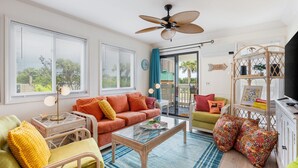 A bright living room with a sofa, armchairs, a coffee table, and a TV stand. - Retro-Themed Condo | 2BR | Perfect Location (Myrtle Beach)