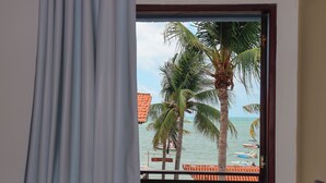 Una ventana con vista a una playa, palmeras y barcos.