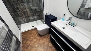 A modern bathroom with a shower, toilet, and vanity.