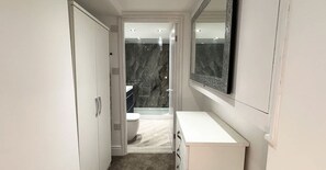 Un bagno moderno con un mobile lavabo bianco, un ampio specchio e un box doccia in marmo.