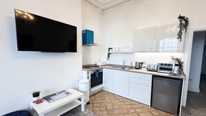 Una cocina compacta con armarios blancos, horno empotrado, microondas y tostadora.