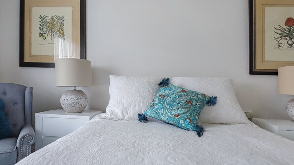 A neatly made bed with a patterned pillow, a lamp on a bedside table, and framed botanical illustrations on the wall. - Heritage on Liebig - Perch at the top of town (Warrnambool)