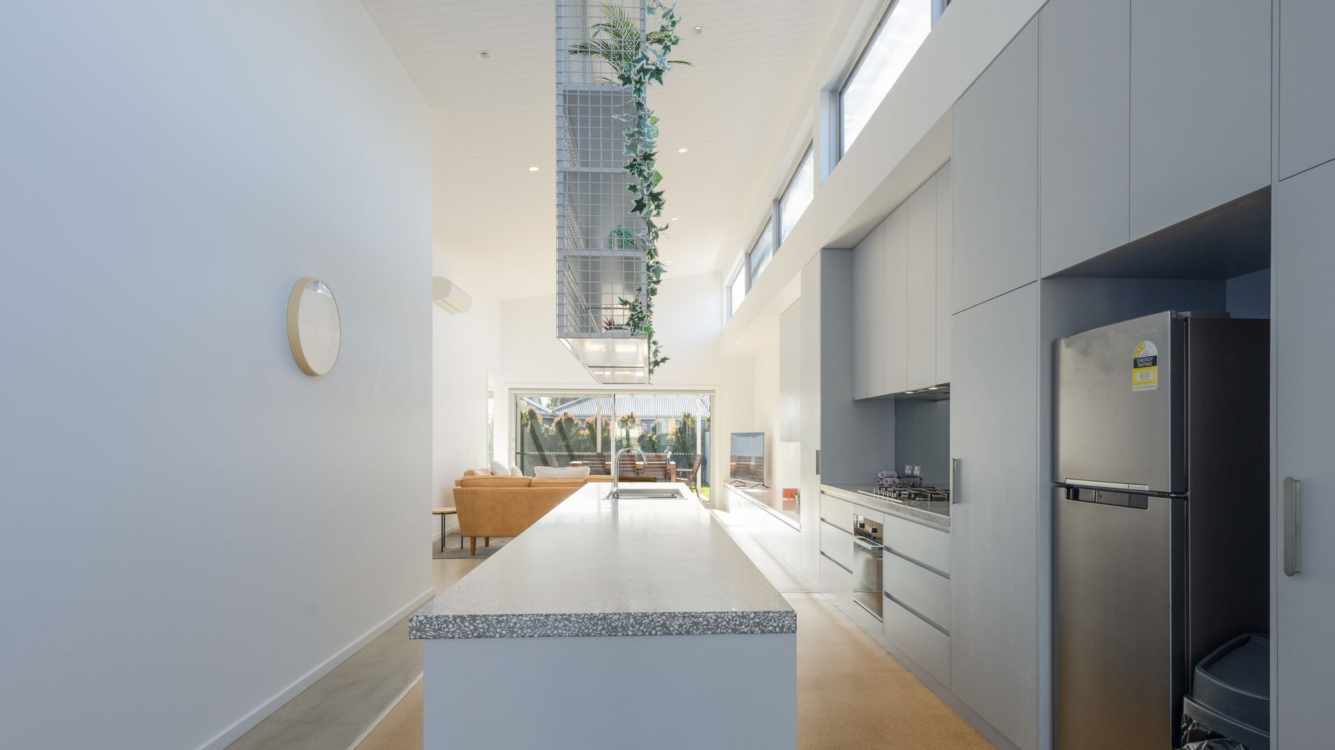 A modern kitchen with a central island, grey cabinetry, and a stainless steel refrigerator.