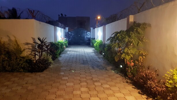 A paved pathway flanked by white walls and plants, leading to a building entrance. - Serenity Villa in Sunny Burusbi Phase 2 (Sukuta)