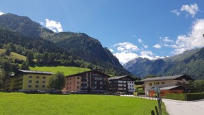 A mountain village with multi-story buildings, a green field, and a clear sky. - Domizil Alpine Retreat 15 With Balcony (Kaprun)