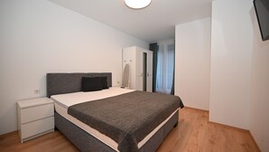 A bedroom with a bed, a nightstand, a wardrobe, and a ceiling light. - Domizil Alpine Retreat 15 With Balcony (Kaprun)