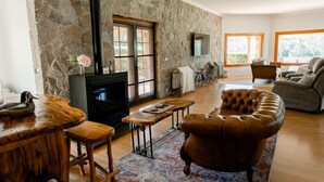 A cozy living room with a stone wall, a fireplace, a leather sofa, and a wooden bar area.