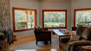 A spacious living room with large windows, a stone wall, and a fireplace.