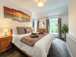 A neatly arranged bedroom with a bed, bedside tables, a lamp, a mirror, and a window with curtains. - 3 bedroom accommodation in Colwyn Bay (Colwyn Bay)