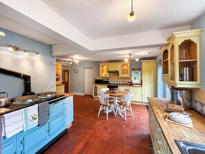 A kitchen with a blue stove, white chairs, and a wooden dining table.