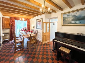 A dining area with a checkered floor, wooden furniture, a piano, and a painting on the wall. - 3 bedroom accommodation in Colwyn Bay (Colwyn Bay)