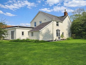 A two-story house with a sloped roof, a chimney, and a well-maintained lawn. - 3 bedroom accommodation in Colwyn Bay (Colwyn Bay)