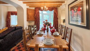 A dining area with a wooden table set for four, surrounded by chairs, with a window and a door in the background. - 3 bedroom accommodation in Colwyn Bay (Colwyn Bay)