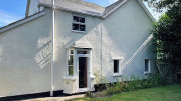 A two-story house with a white exterior, a small porch, and a visible chimney.